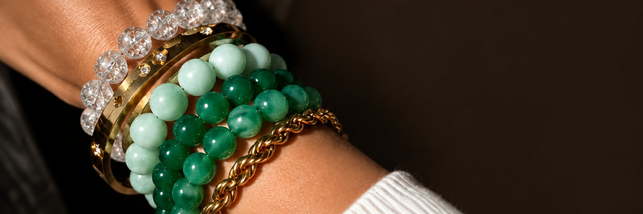 Accumulation de bracelets en jade vert, cristal et métal doré au poignet
